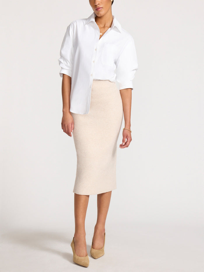 Woman wearing an oversized white button-up shirt with a beige knit midi skirt and tan heels