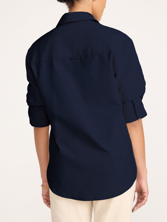 Button-down shirt in navy, back view with rolled sleeves over beige pants