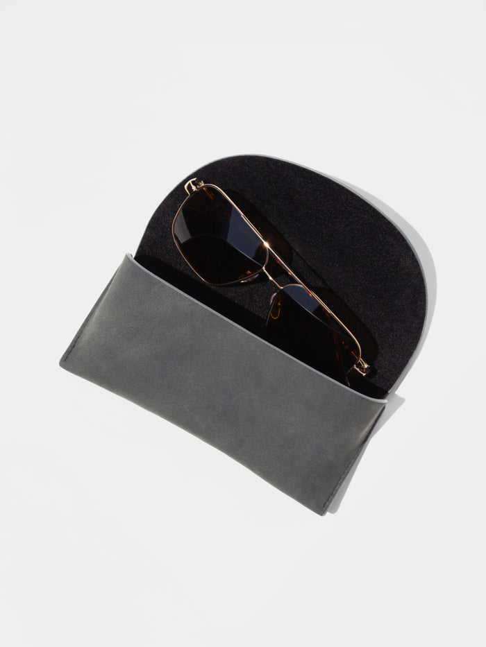 Gold-frame aviator sunglasses tucked inside a soft gray foldover case