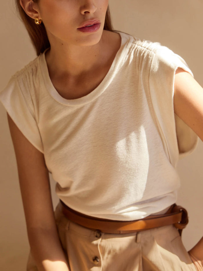Cream crewneck t-shirt, tucked into beige pants with a brown belt