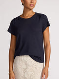 Woman wearing a navy linen t-shirt tucked into a cream lace midi skirt.