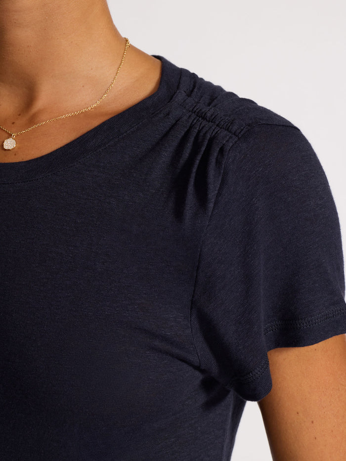 Close-up of a navy linen t-shirt with a gathered neckline, worn with a gold necklace.