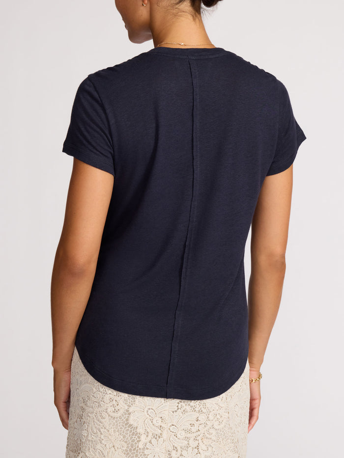 Back view of a navy linen t-shirt worn with a cream lace midi skirt.