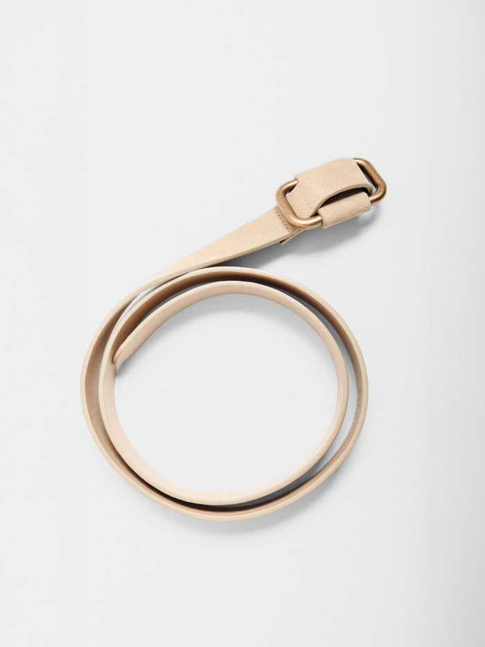 Light tan suede belt with a gold buckle, coiled on a plain background