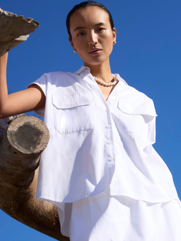 Woman wearing a white cargo shirt with flap pockets against a blue sky