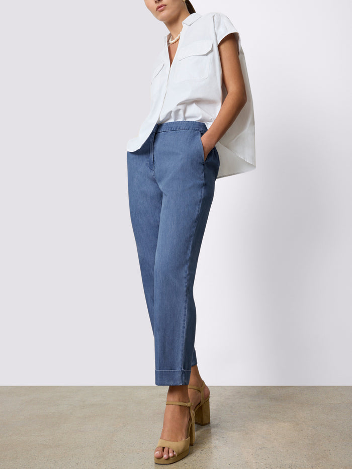Woman wearing a white popover shirt with blue wide-leg denim pants and tan heeled sandals