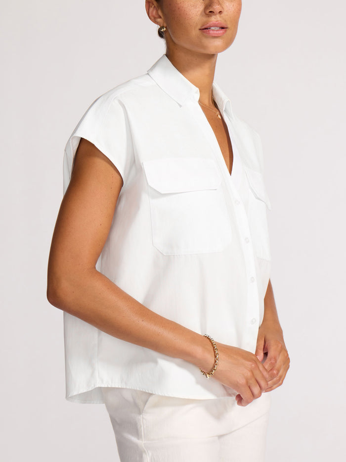 Model wearing a white short-sleeve shirt with a chest pocket, shown from the side