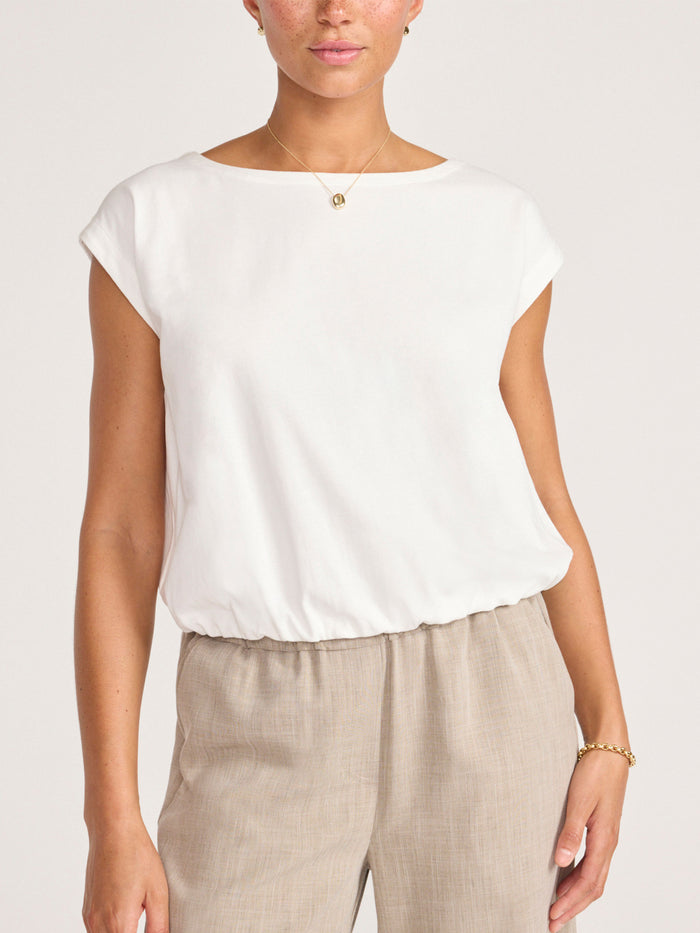 Boat-neck top in ivory with cap sleeves, styled with beige linen pants
