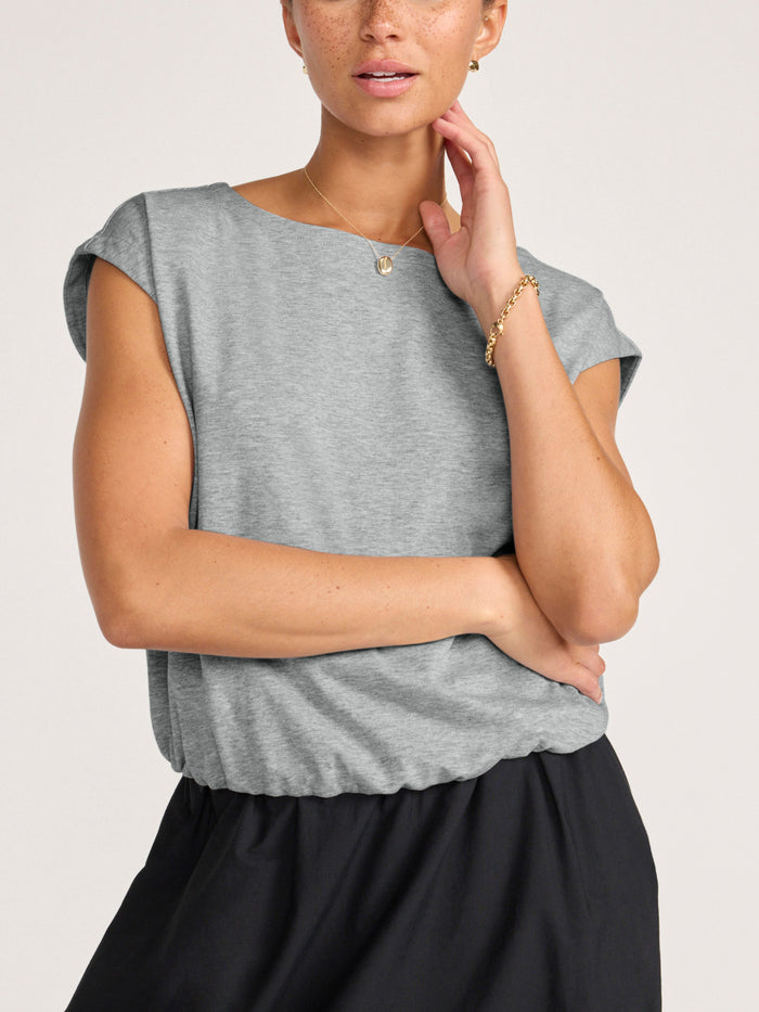 Close-up of a woman wearing a pebble grey sleeveless top with a black skirt