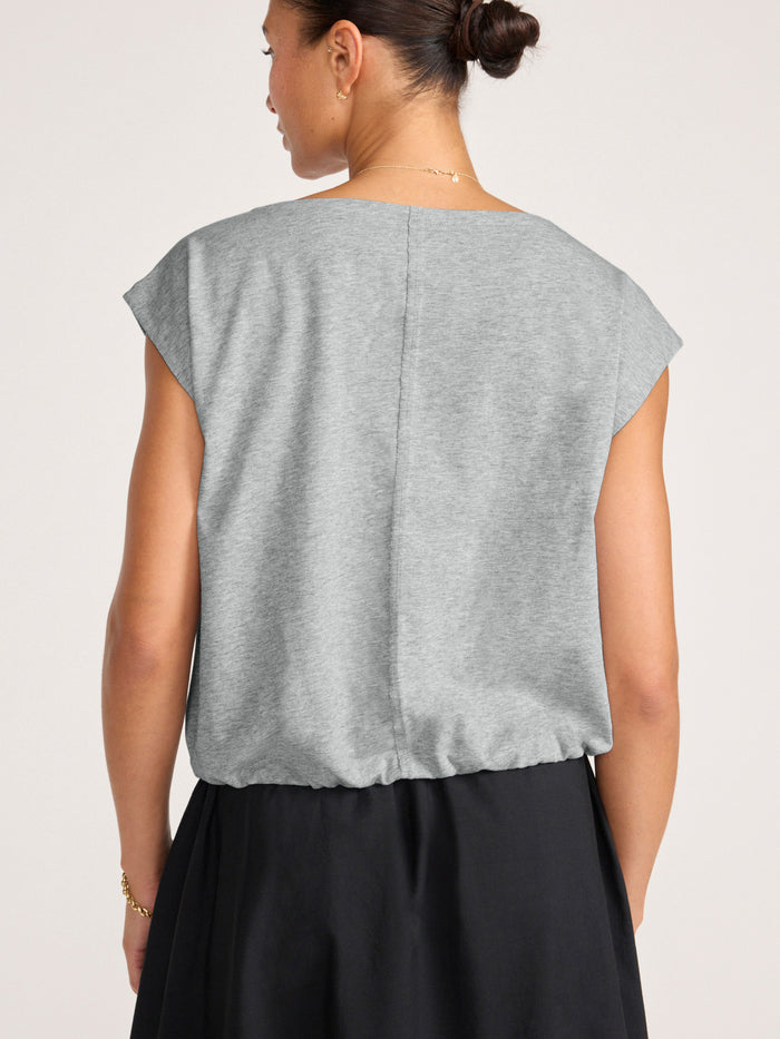 Woman wearing a pebble grey sleeveless top with a cinched hem, back view