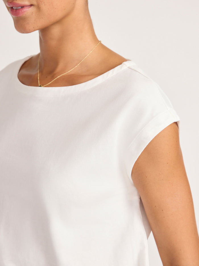 Close-up of the crew neckline on a white cap-sleeve top